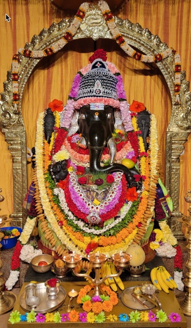 A village sanctum dressed for worship: the murti garlanded in marigold and silk